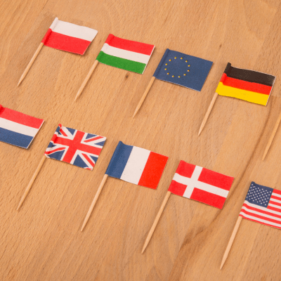 Miniature flags of different countries on a wooden table