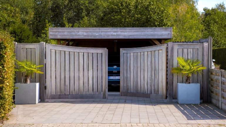 Un portail pivotant en bois avec des planches verticales pour l'entrée d'un garage