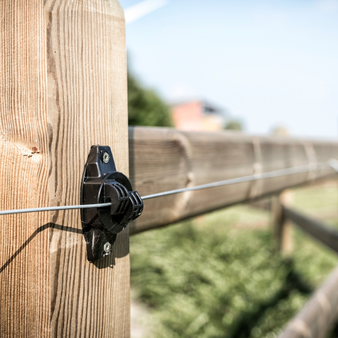 A close up of a wooden fence with a wire attached to it.