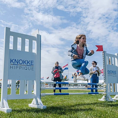 A girl jumping from a jumping obstacle