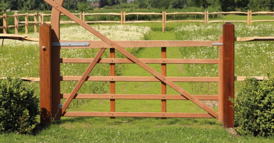 A wooden field gate with an arch connected to a wooden fence.